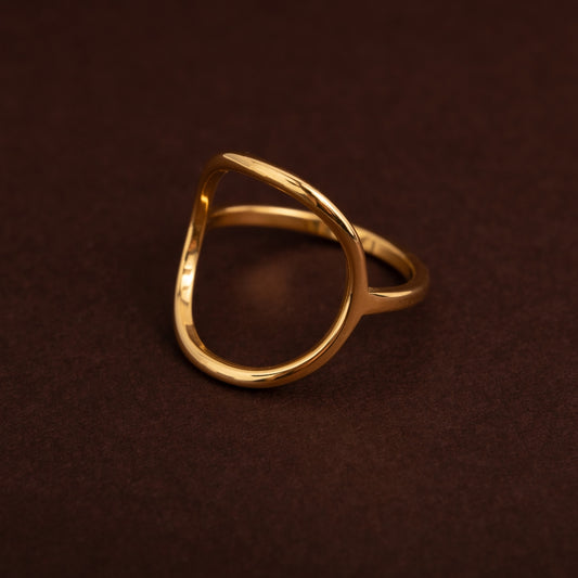 Anel dourado em aço inoxidável com design de círculo grande aberto e vazado, estilo minimalista e orgânico.
