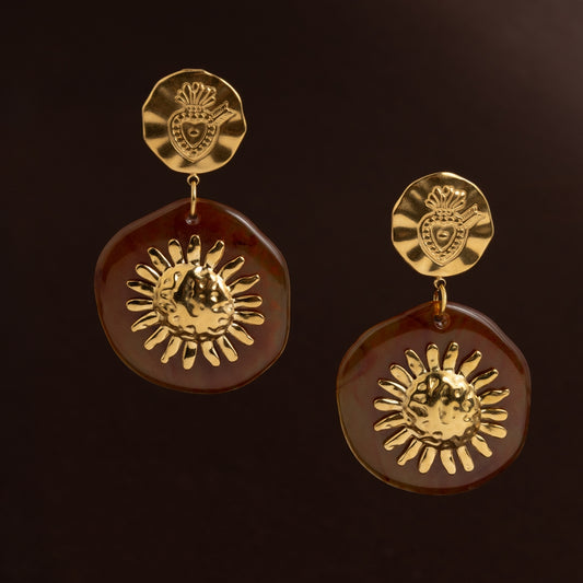 Brincos grandes dourados com base de coração sagrado e pendente de resina castanha com sol dourado martelado no centro. Jóia estilo vintage e orgânico.