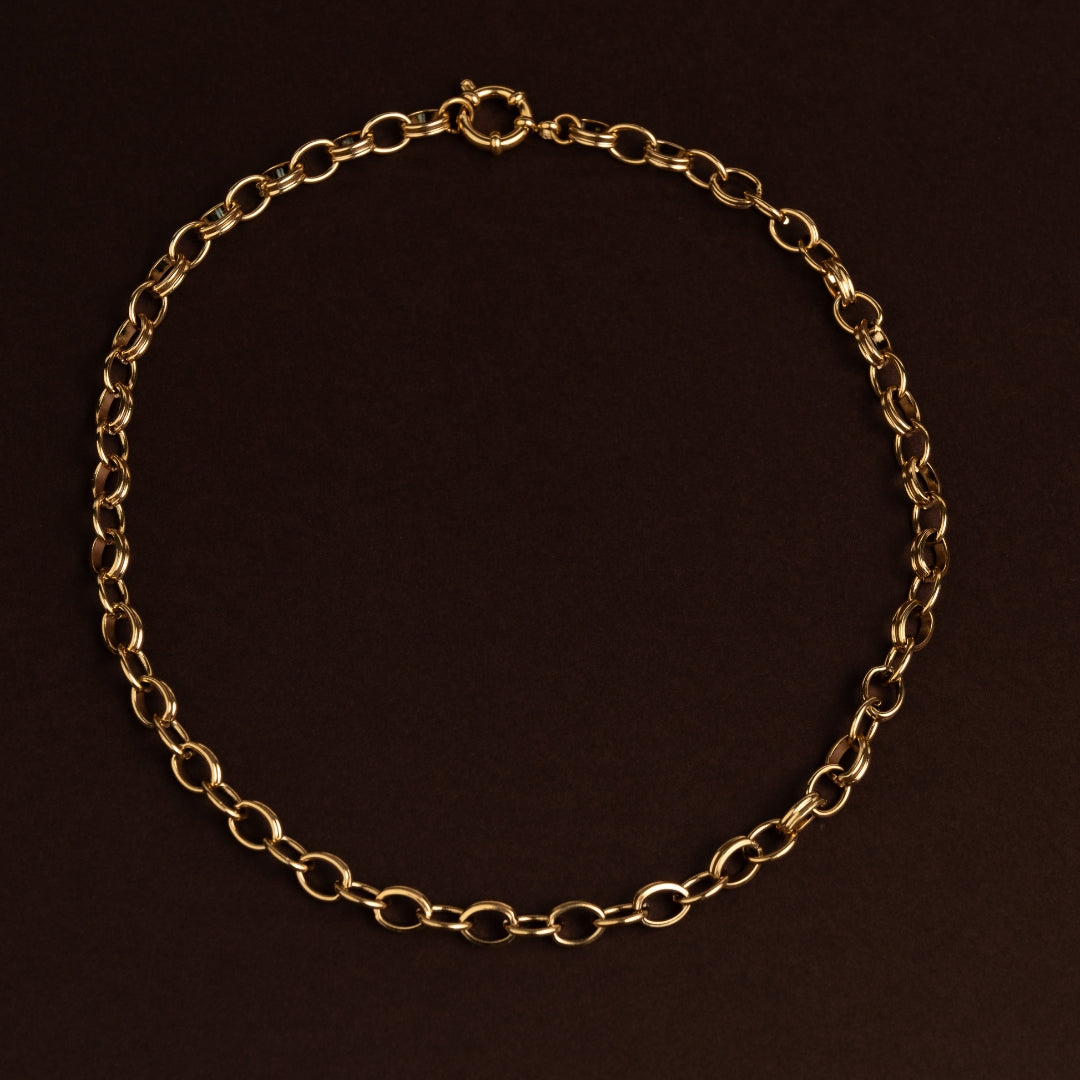 Colar de corrente dourada em aço inoxidável com design de elos duplos redondos entrelaçados e fecho frontal.