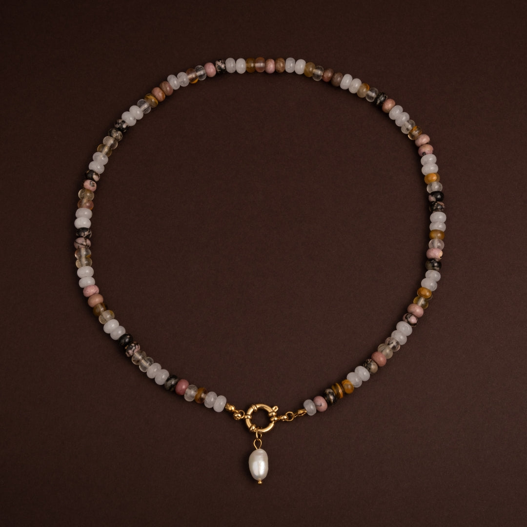 Vista completa do colar Natureza com mix de pedras naturais redondas e fecho central decorativo sobre fundo escuro.