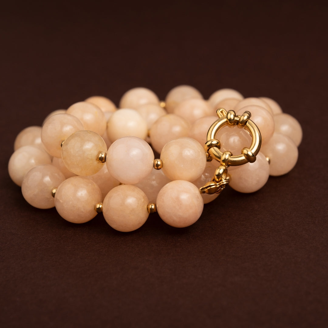 Detalhe do fecho boia dourado em aço inoxidável e das contas brilhantes em tom champanhe do colar Seda.