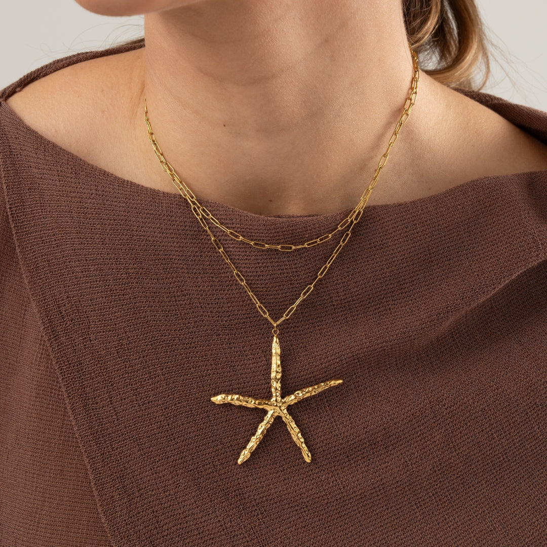 Modelo a usar o Colar Estrela do Mar maxi em aço inoxidável dourado com duas voltas na corrente