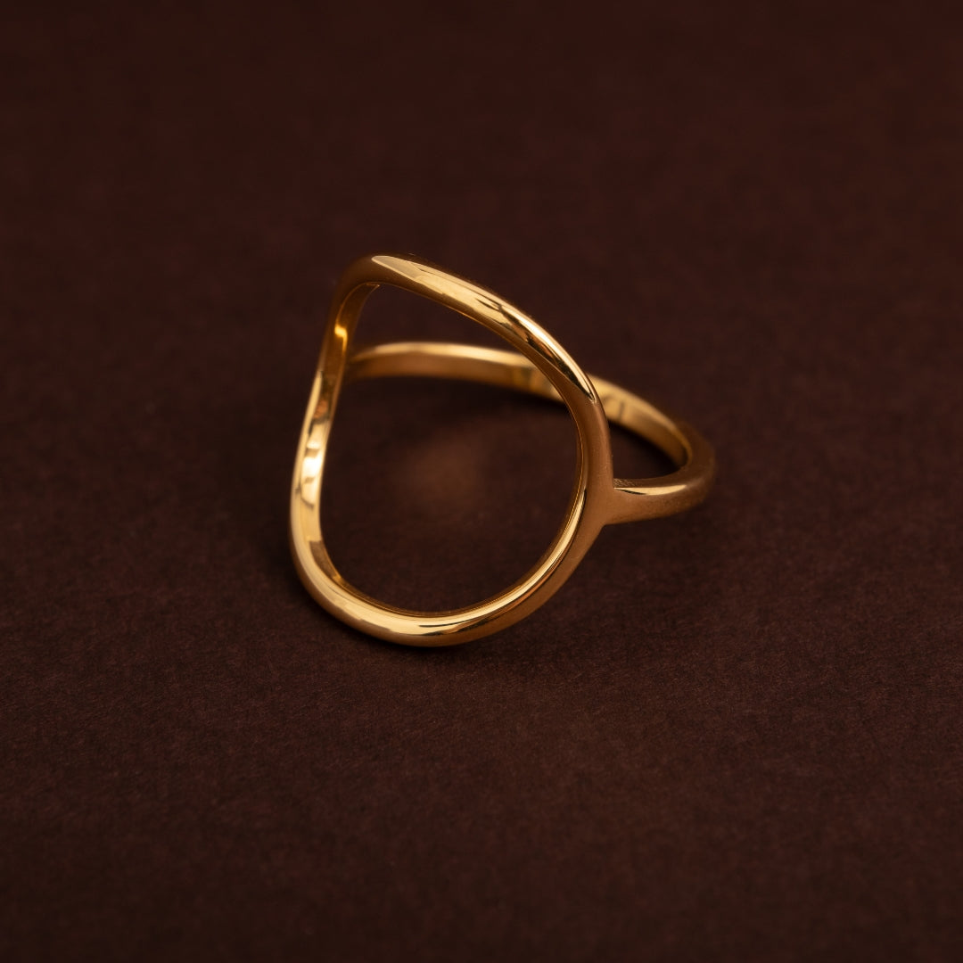 Anel dourado em aço inoxidável com design de círculo grande aberto e vazado, estilo minimalista e orgânico.