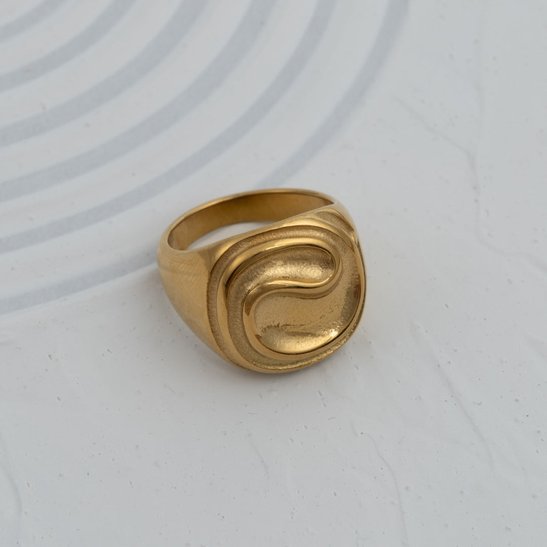 Anel Trace sinete em aço inoxidável dourado e prateado com relevo ondulado design contemporâneo coleção Fuse.