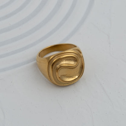 Anel Trace sinete em aço inoxidável dourado e prateado com relevo ondulado design contemporâneo coleção Fuse.