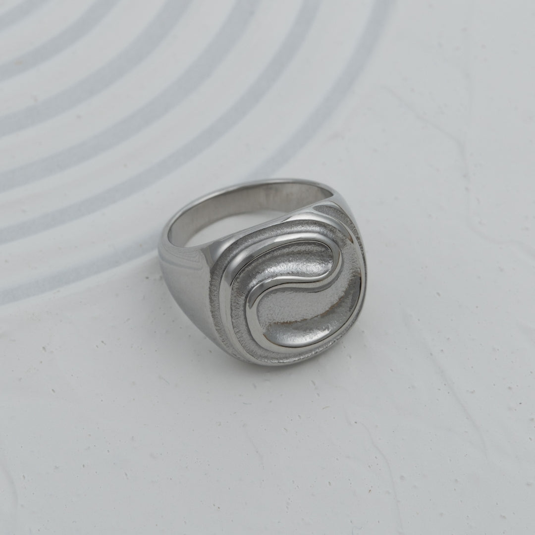 Anel Trace sinete em aço inoxidável dourado e prateado com relevo ondulado design contemporâneo coleção Fuse.
