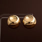 Brincos de botão redondos e volumosos em aço inoxidável dourado com acabamento brilhante estilo chunky dome.