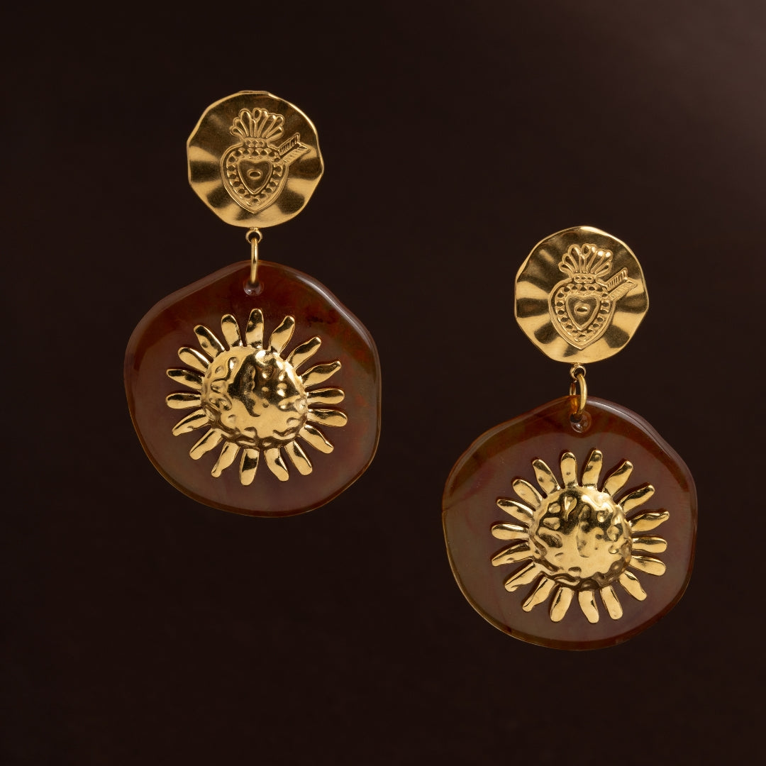 Brincos grandes dourados com base de coração sagrado e pendente de resina castanha com sol dourado martelado no centro. Jóia estilo vintage e orgânico.