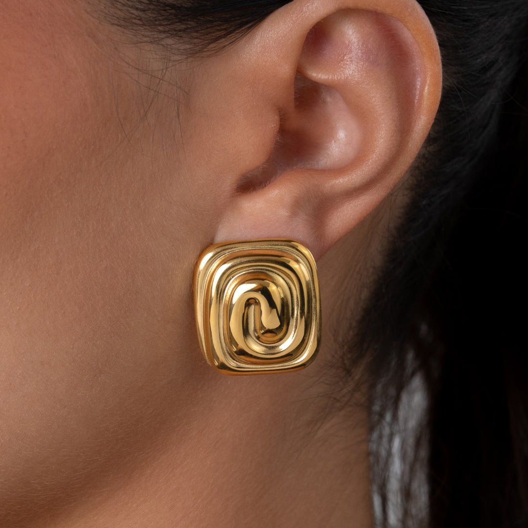 Brincos Mira quadrados em aço inoxidável dourado com design de espiral central coleção Fuse joalharia urbana leve.
