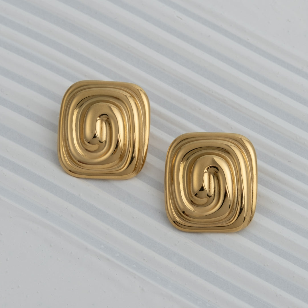 Brincos Mira quadrados em aço inoxidável dourado com design de espiral central coleção Fuse joalharia urbana leve.