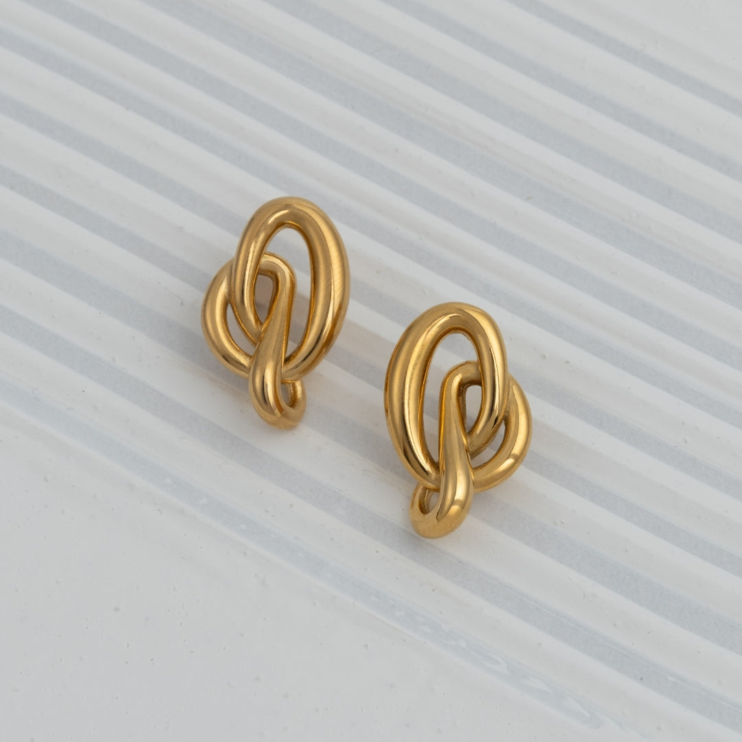 Brincos Chrome Flow em aço inoxidável dourado e prateado design de nó fluido coleção Fuse joalharia contemporânea.
