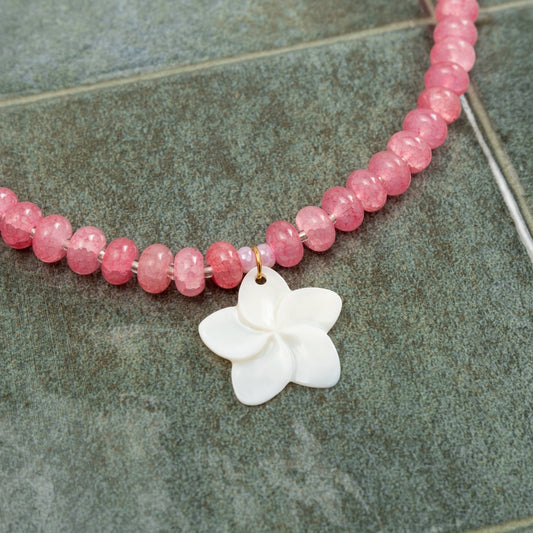 Detalhe em grande plano do Colar Aloha com contas de pedras naturais rosa e pendente central em forma de flor esculpida em madrepérola